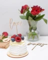 Drewniany topper na tort Love na deserze z owocami, obok wazon z różami.