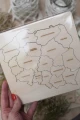 Drewniane puzzle - mapa Polski z zaznaczonymi województwami, widoczne z bliskiej perspektywy, w opakowaniu. Trzymane przez osobę.