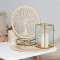 Drewniane drzewo życia w kole na białym stoliku, w towarzystwie świecznika i dekoracji.