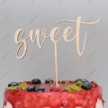 Drewniany topper na tort Sweet ze sklejki brzozowej, umieszczony na torcie z owocami.