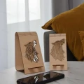 Dwa stojaki na telefon wilk geometryczny ze sklejki brzozowej, z wyciętym wzorem wilka, na tle poduszki i smartfona.