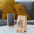Stojak na telefon z koniem geometrycznym, wykonany ze sklejki brzozowej. Widoczne dwa stojaki, jeden z telefonem.