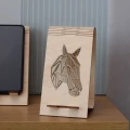 Stojak na telefon z drewna brzozowego z geometryczną głową konia. Widoczny profil konia na tle jasnego drewna.