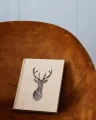 Segregator biurowy jeleń geometryczny ze sklejki brzozowej na fotelu. Widoczny wzór jelenia na okładce.