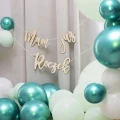 Drewniana girlanda Mam już Roczek na tle balonów w kolorach bieli i turkusu.