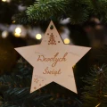Drewniana gwiazdka z grawerem Wesołych Świąt zawieszona na choince. Ozdoba świąteczna ze sklejki brzozowej.