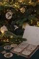 Drewniane pudełko z bożonarodzeniowymi zawieszkami z brzozowej sklejki. Widok pudełka otwartego, zawieszki ułożone w przegródkach.