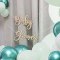 Drewniana girlanda Baby Shower na tle balonów w kolorach bieli i zieleni.