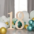 Drewniana cyfra 18 z dekorem, ozdoba urodzinowa stojąca, z balonami w tle.